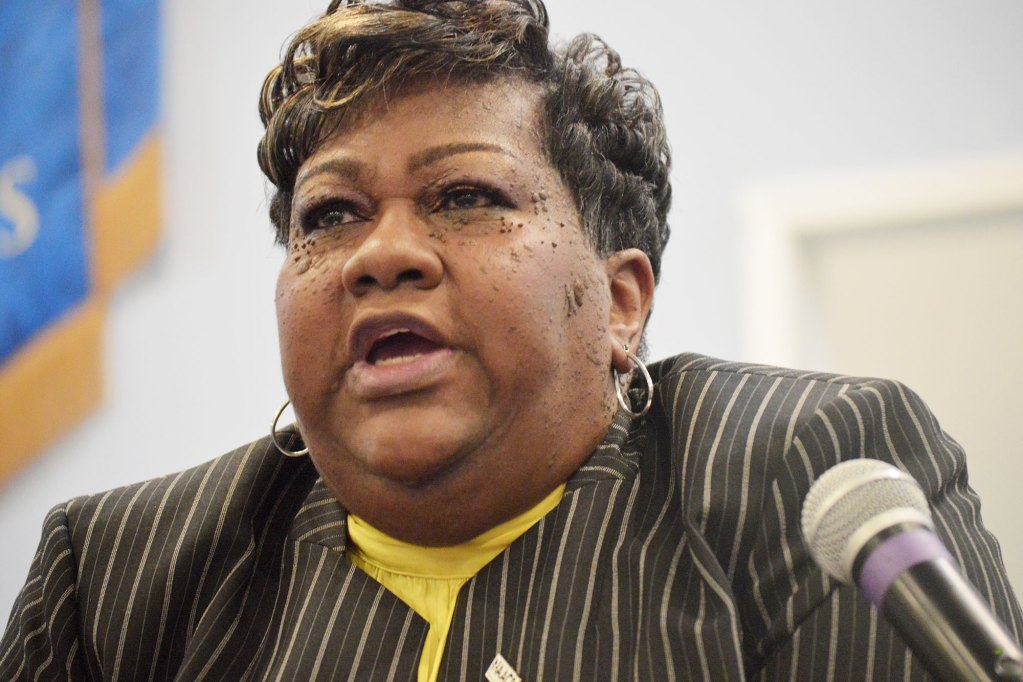 A lady wearing a black striped jacket with a yellow under shirt