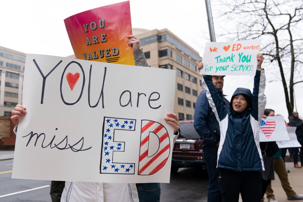 Supporters hold signs and cheer Education Department employees, one sign reading “We love ED workers”