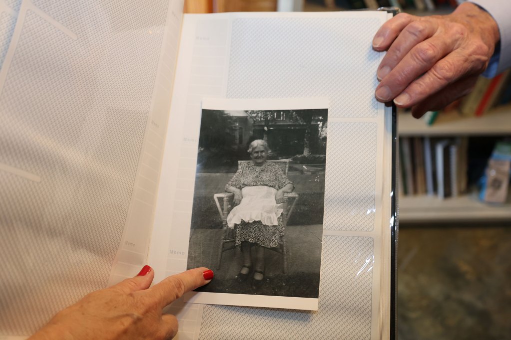 A black and white photo of a woman sitting in a chair wearing a black and white dress with a white apron around her