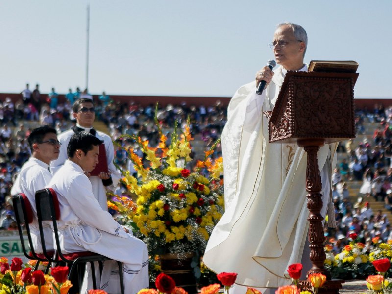 The New Pope speaking to a stadium of people wearing a white robe and holding a mic