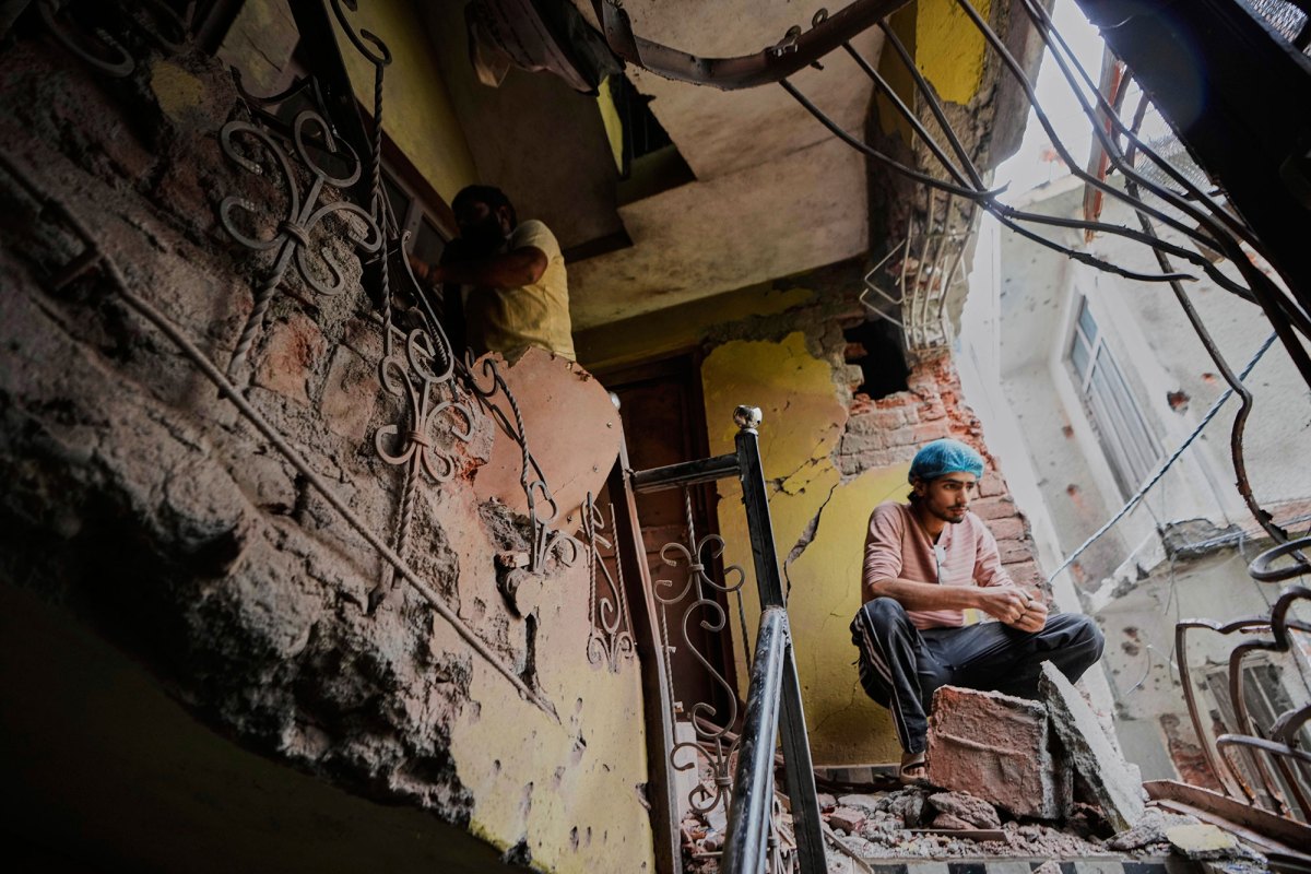A person sits in his house damaged by Pakistani artillery shelling