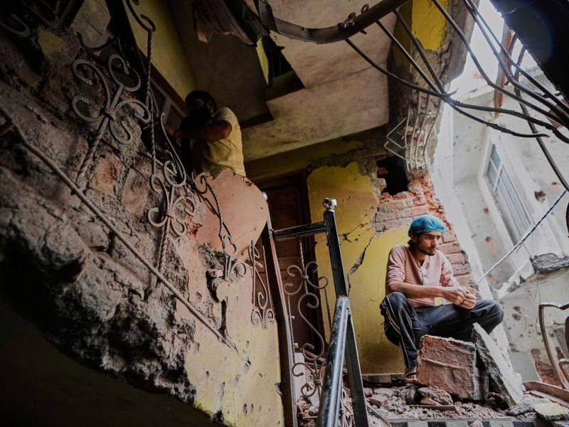 A person sits in his house damaged by Pakistani artillery shelling