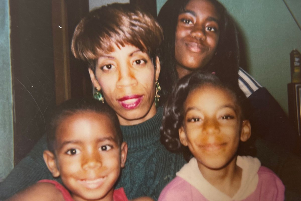 A mother and her three children pose together, smiling