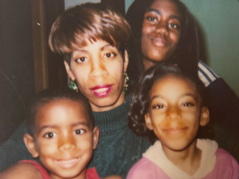 A mother and her three children pose together, smiling