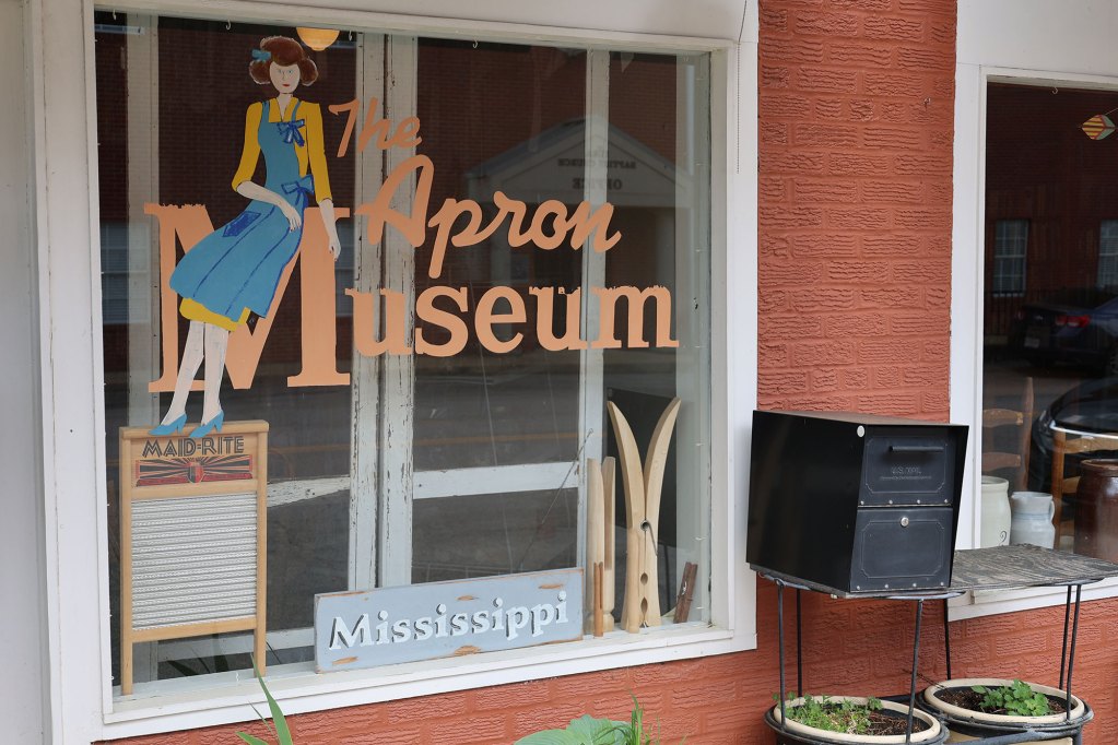 A window seal of building with an illustration of a woman on it and the words The Apron Museum written on it