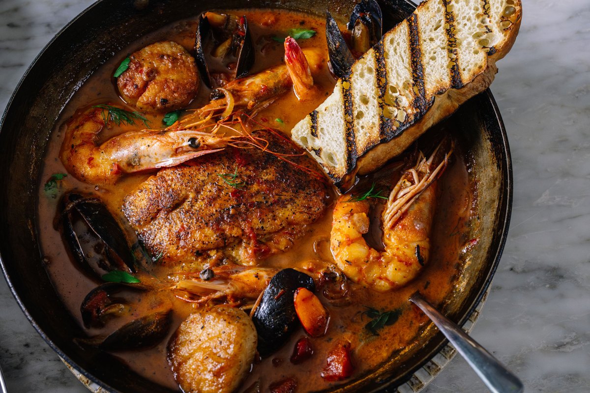 A bowl containing a seafood dish that includes shrimp, oysters and other ingredients