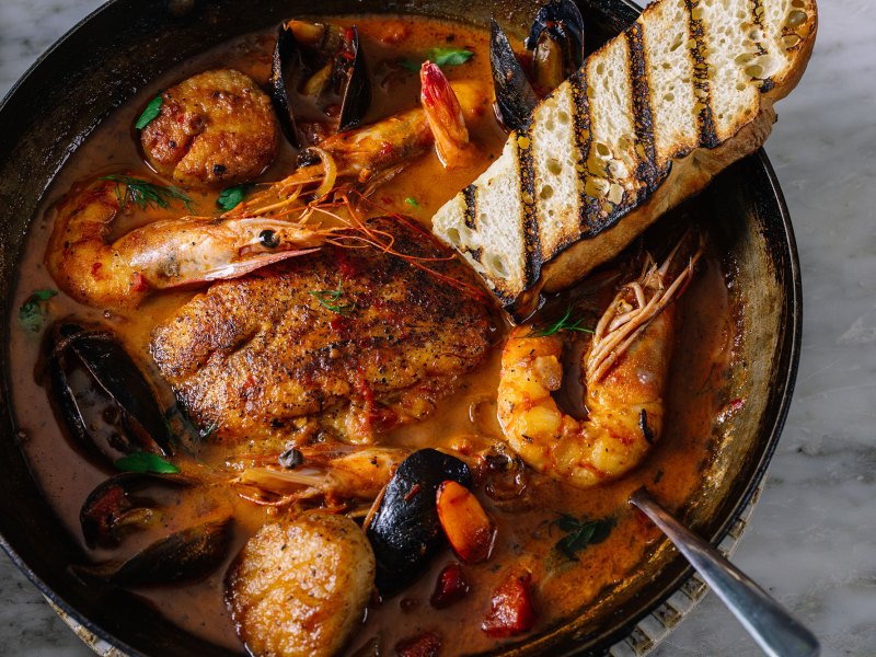 A bowl containing a seafood dish that includes shrimp, oysters and other ingredients