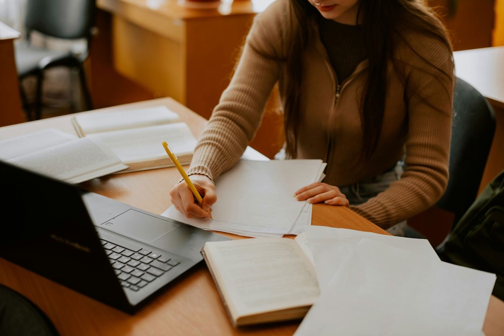 A slightly overhead view of a woman sitting at a desk, writing