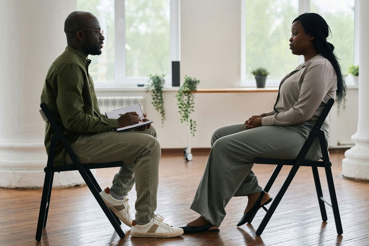 Side view of a young man with notebook in hands talking with a woman in the opposite chair