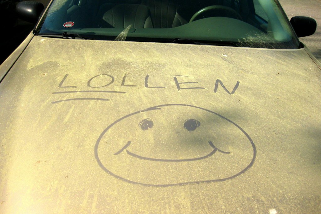A car covered in yellow. Someone drew a smiley face with the words 'LOLLEN,' with LOL underlined