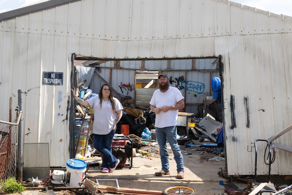 A woman and man standing under a white metal shed