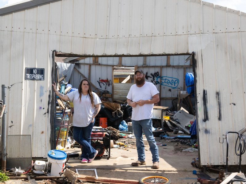 A woman and man standing under a white metal shed