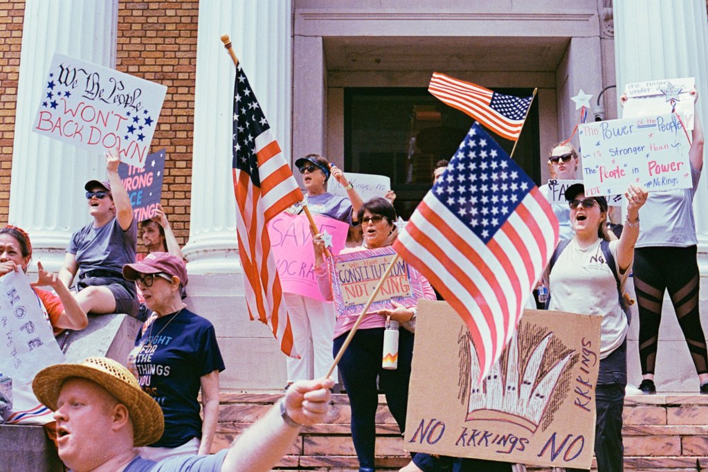 Protesters wave US Flags and hold signs that read "no kings" and "We the people won't back down"