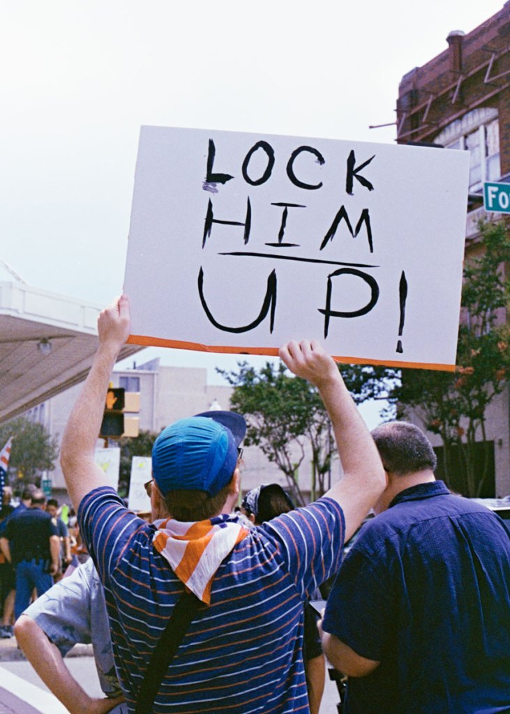 A protester holds a sign that reads "Lock him up"