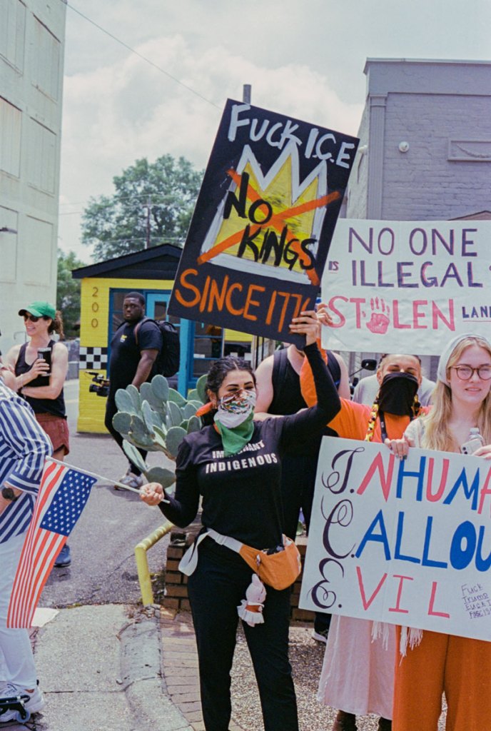Protesters hold signs that read "fuck ice no kings since 1776" and "No one is illegal on stolen land"