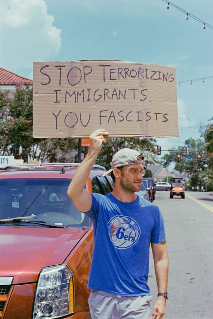 A protester holds a sign that reads "Stop terrorizing immigrants, you fascists"