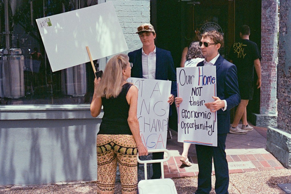 Counter protesters hold signs that read "Our home is not their economic opportunity"