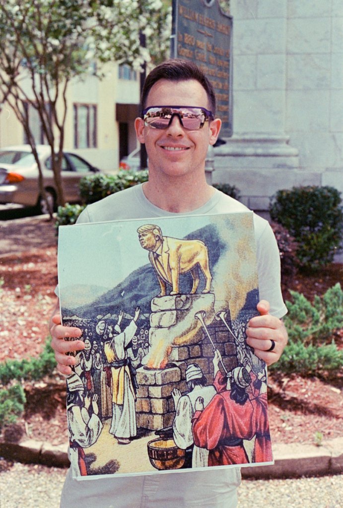 A man holds a image depicting Trump as a biblical golden calf