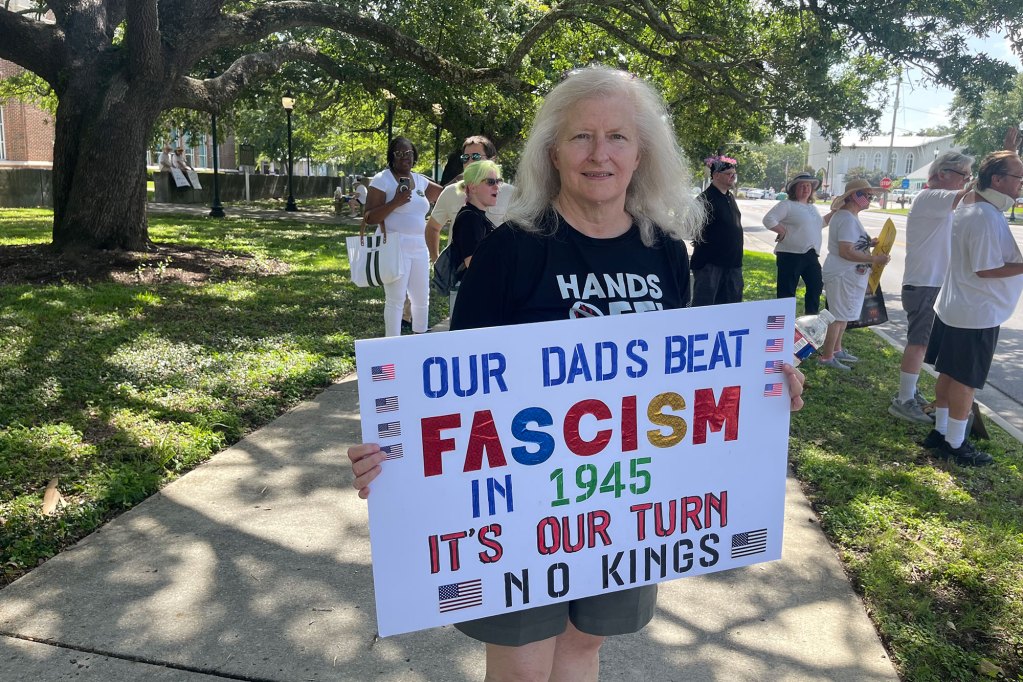 A protester holds a sign that reads "Our Dad beat fascism in 1945. It's our turn. No kings."
