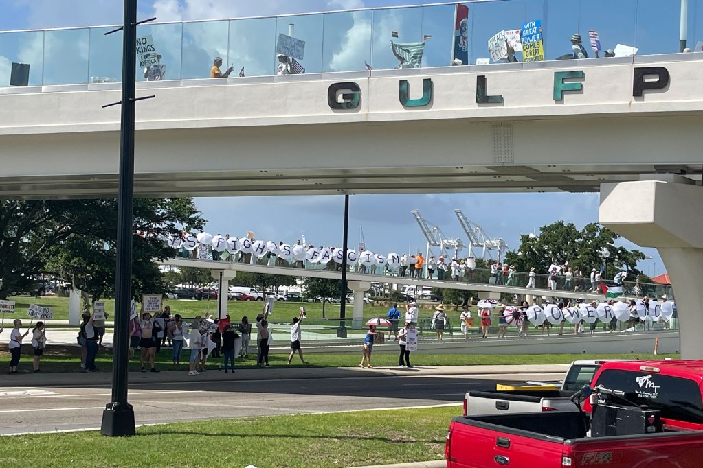 Protesters holding signs on and below a bridge