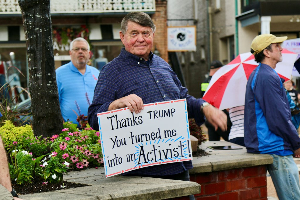 A crowd of protesters carry signs, one reads "Thanks Trump you turned me into an activist"