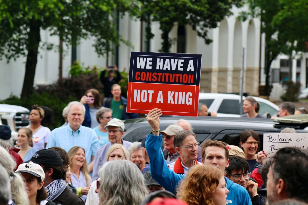 Protesters outside holding signs, one reads "We have a constitution, not a king"