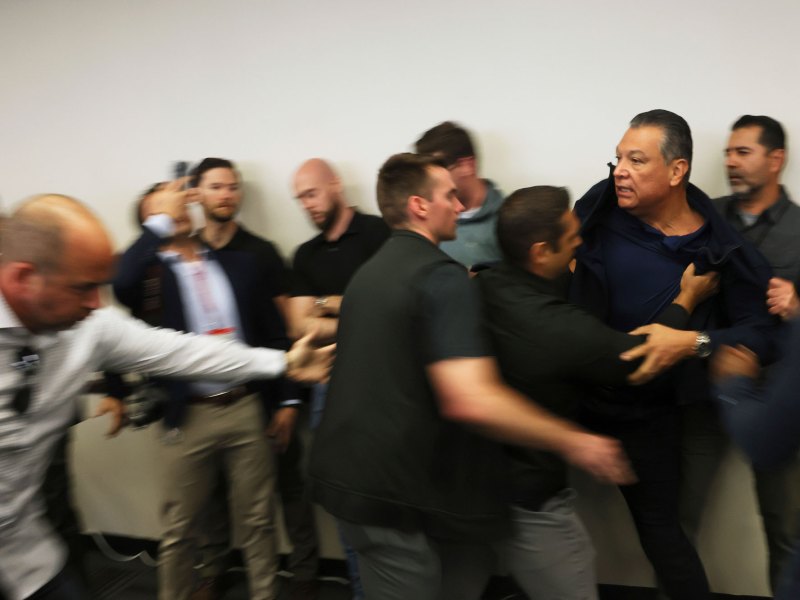 A mad scramble as security guards push a man out of the room