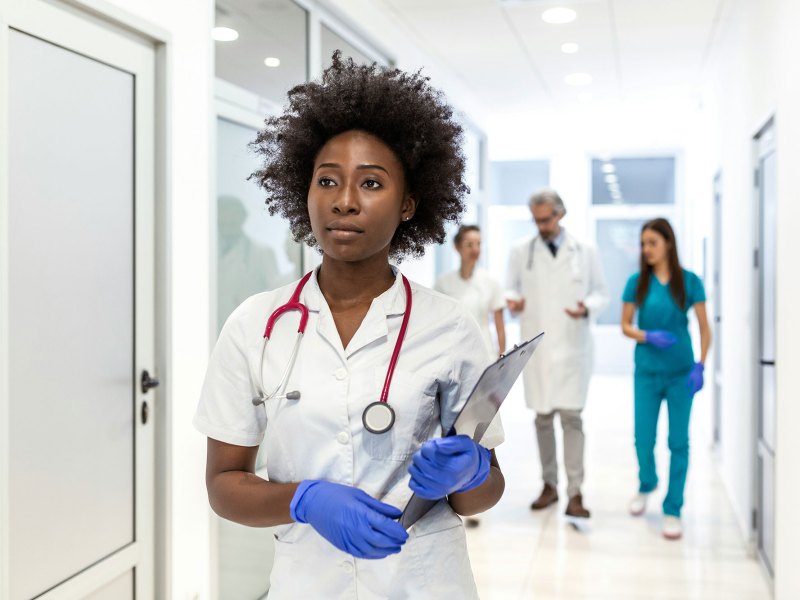 Woman with black hair in a white coat with blue gloves on her hands