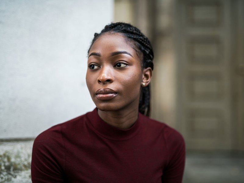 Woman with braids and wearing a maroon shirt