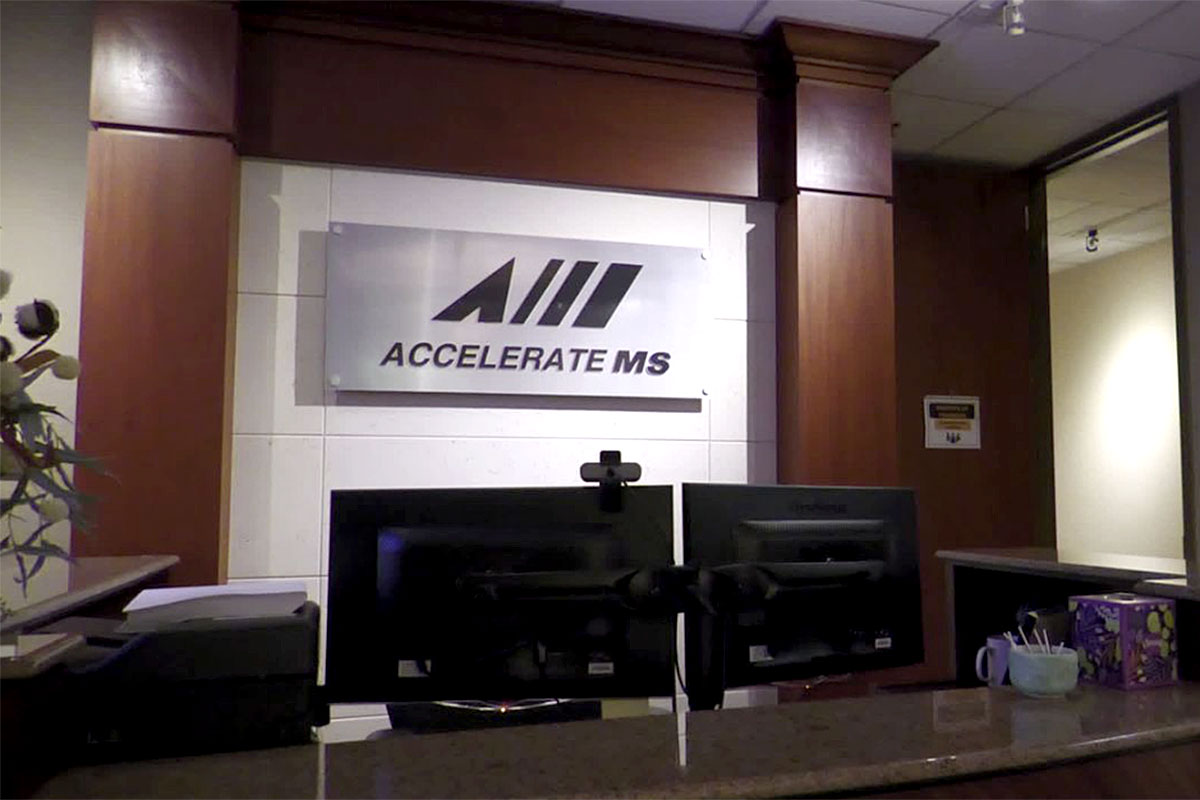 Reception area at the AccelerateMS workforce development office, featuring two computer monitors and a sign reading “Accelerate MS.”