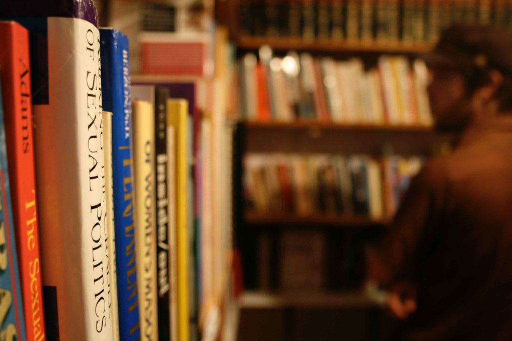 A view inside a bookstore with shelves of books to the right and in the background as a person peruses the options