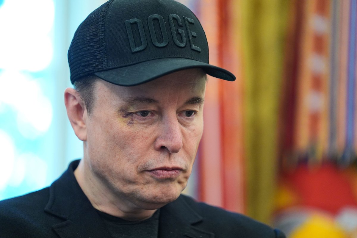A closeup of Elon Musk in the White House, wearing a black DOGE cap and sporting a black eye