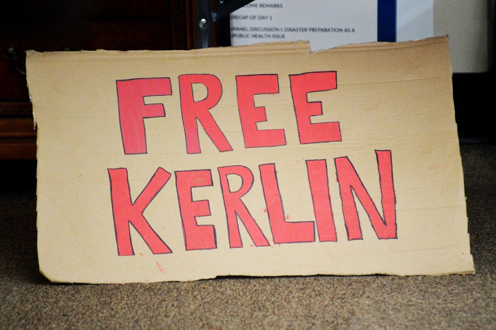 A cardboard sign that reads FREE KERLIN in big red lettering