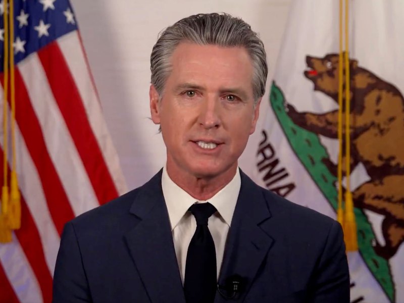 Gov. Gavin Newsom speaking in front of US and California flags