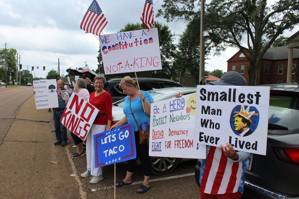 Protesters hold up signs, one reads "We have a constitution not a king"