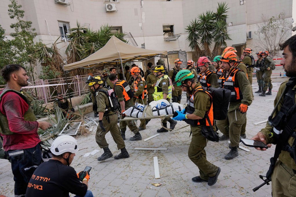 soldiers and rescue workers carry a body from a destroyed building
