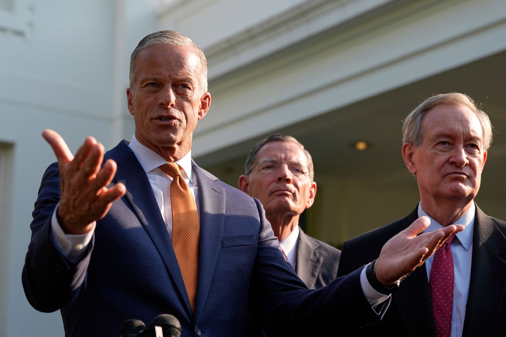 Three senators speaking outside at a podium