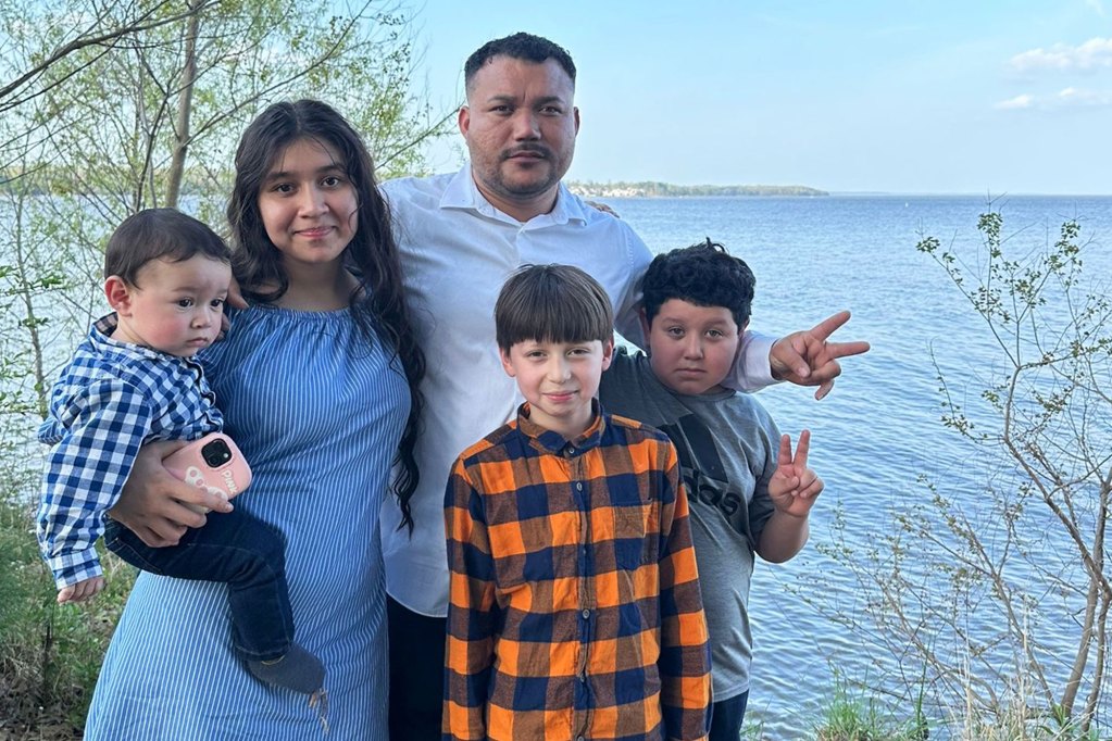 A family of five pose for a photo by a lake