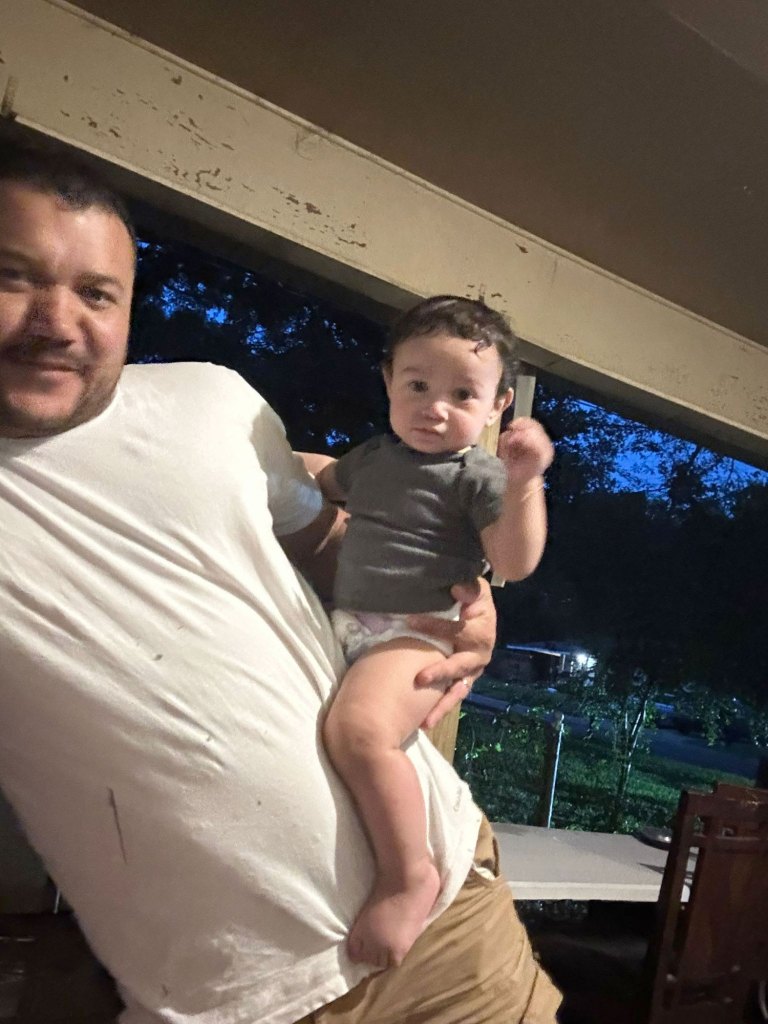 A man holds his young child on his hip