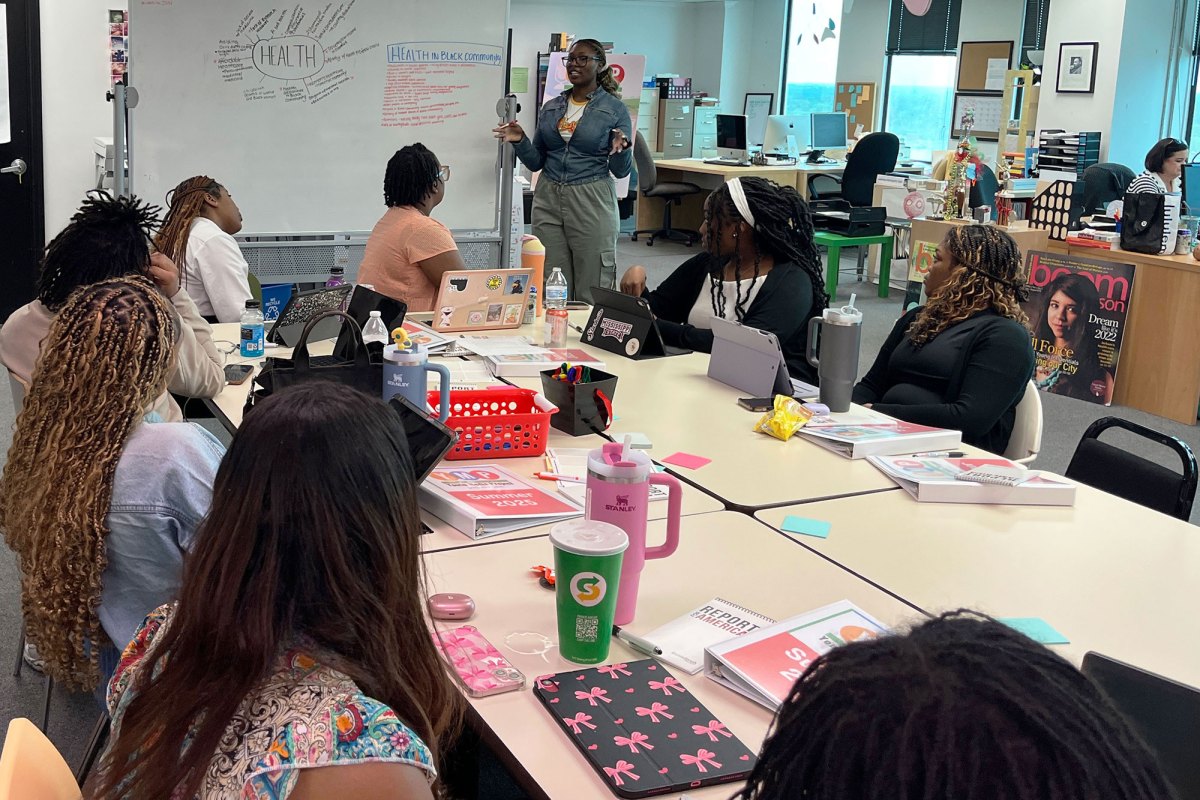 Kiden-Aloyse Smith in front of a whiteboard, teaching the Youth Media Project class