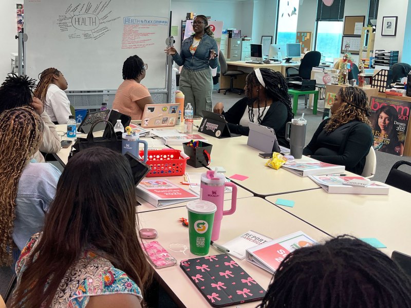 Kiden-Aloyse Smith in front of a whiteboard, teaching the Youth Media Project class