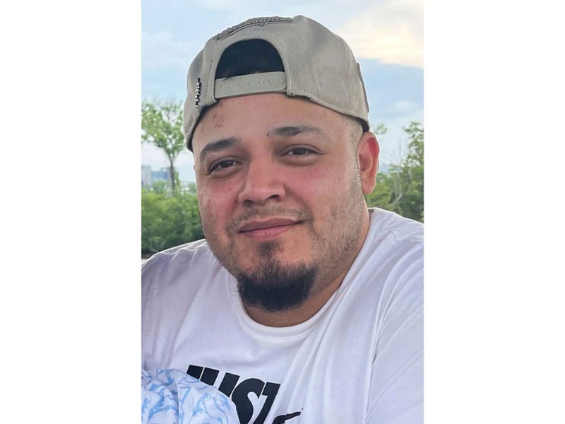 A man wearing a backwards baseball cap, smiling