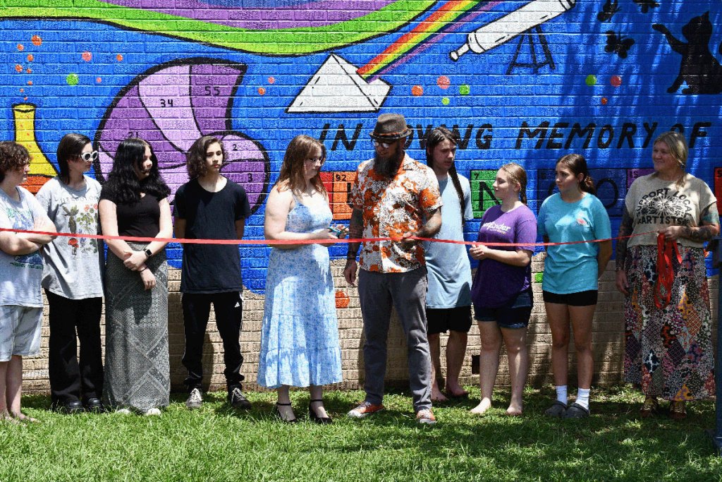 People hold a red ribbon in front of a newly painted wall mural
