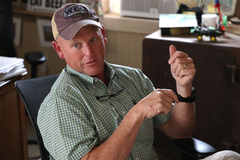 A man, seated in a home office, speaks with hands gesturing