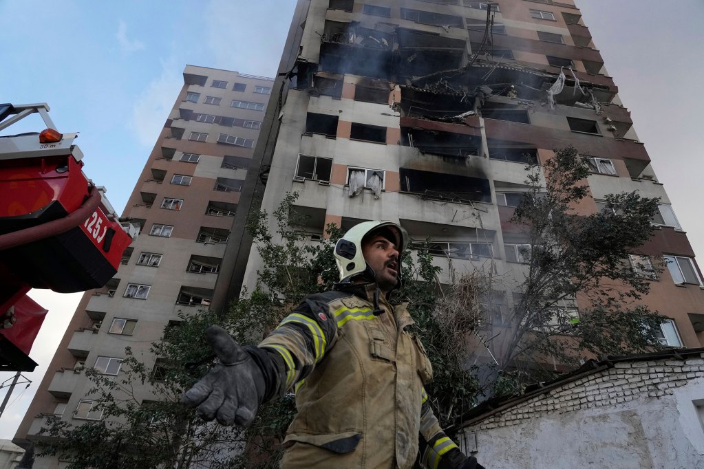 A firefighter helps in front of a building with explosion damage