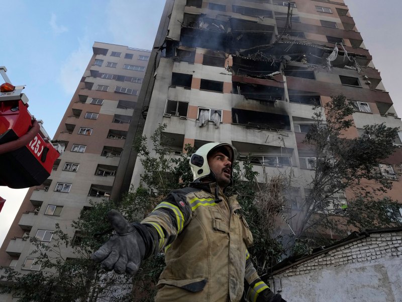 A firefighter helps in front of a building with explosion damage