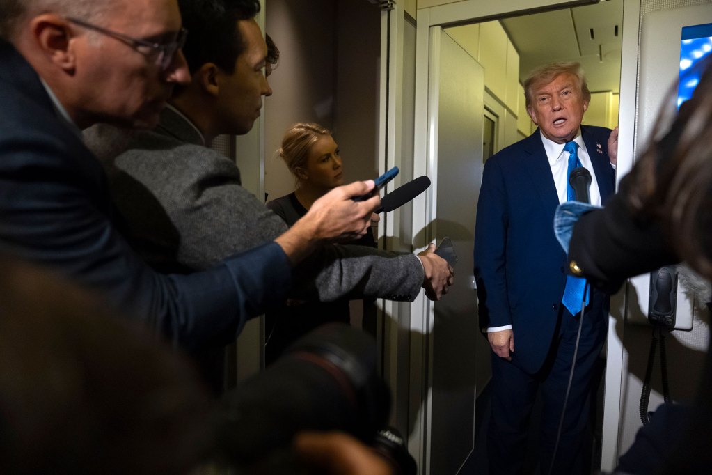 Reporters crowd around a door to ask Donald Trump questions