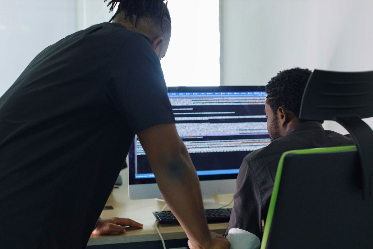 Two men looking at a coding screen