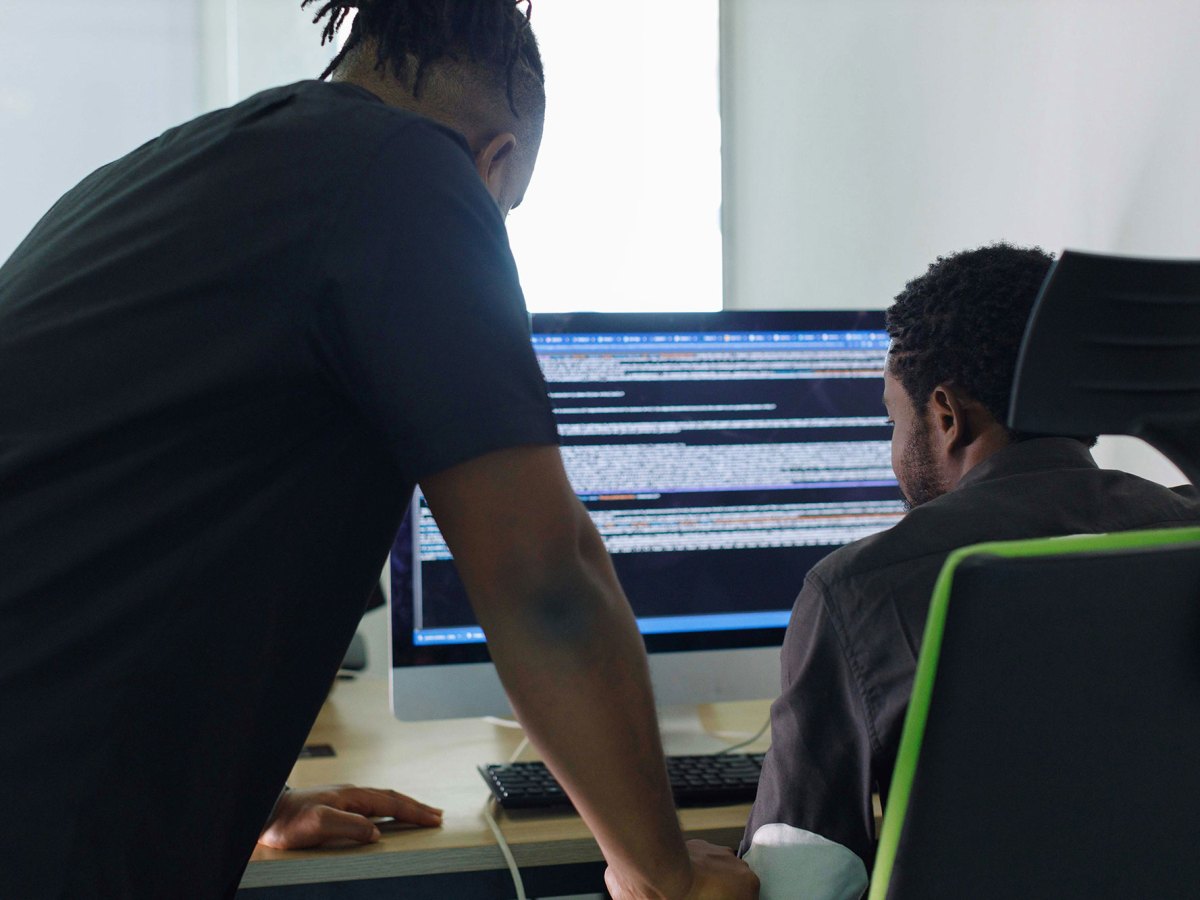 Two men looking at a coding screen