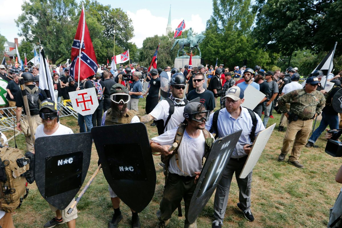 A gathering of demonstrators wearing shields and goggles, others carrying the Confederate flag behind them